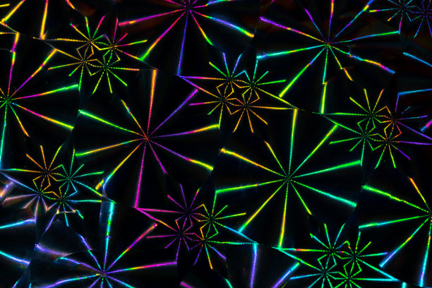 近距离的照片。充满活力的全息霓虹灯颜色重复几何装饰图案的反射闪亮的表面击中光。90年代迪斯科派对背景。图片下载