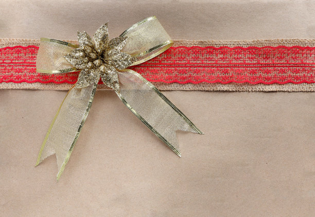 俯视图照片圣诞礼物包裹在牛皮纸与金蝴蝶结闪闪发光。2023年新年快乐。漂亮的圣诞礼物。空间的文本。图片下载