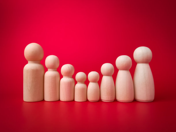 红色背景上按身高排列的木头人大家庭。图片下载