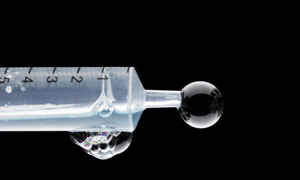 医用注射器在注射器的压力下喷出液体，有气泡和滴水图片下载