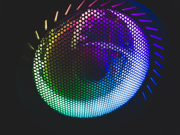 电脑风扇的彩色led灯穿过防护网格。照明在黑暗中发光。抽象的背景图片下载