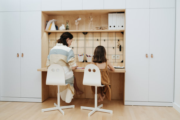 年轻的妈妈在帮可爱的小女儿做作业图片下载