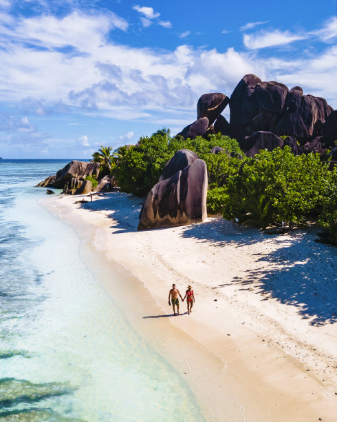塞舌尔La Digue的Anse Source d'Argent，一对年轻男女在塞舌尔的热带海滩上进行豪华度假。热带海滩Anse Source d'Argent，拉迪格塞舌尔图片下载