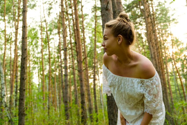 一位身穿白裙的年轻女子在森林中跳舞。自由的概念和与自然的关系。图片下载
