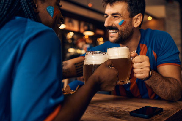 在世界杯期间，一对球迷在酒吧里用啤酒干杯庆祝。图片下载