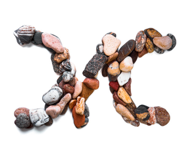 在白色孤立的背景上用光滑的石头刻出的字母。河边的石头上排列着一个字母，细节，特写。有选择性的重点图片下载