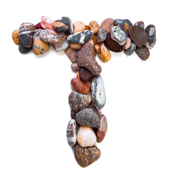 在白色孤立的背景上用光滑的石头刻出的字母。河边的石头上排列着一个字母，细节，特写。有选择性的重点图片下载