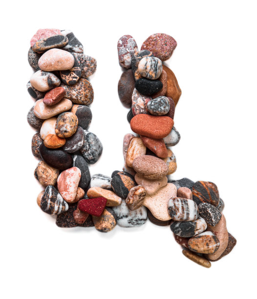 在白色孤立的背景上用光滑的石头刻出的字母。河边的石头上排列着一个字母，细节，特写。有选择性的重点图片下载