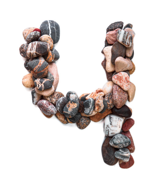 在白色孤立的背景上用光滑的石头刻出的字母。河边的石头上排列着一个字母，细节，特写。有选择性的重点图片下载