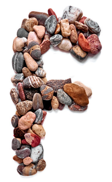在白色孤立的背景上用光滑的石头刻出的字母。河边的石头上排列着一个字母，细节，特写。有选择性的重点图片下载