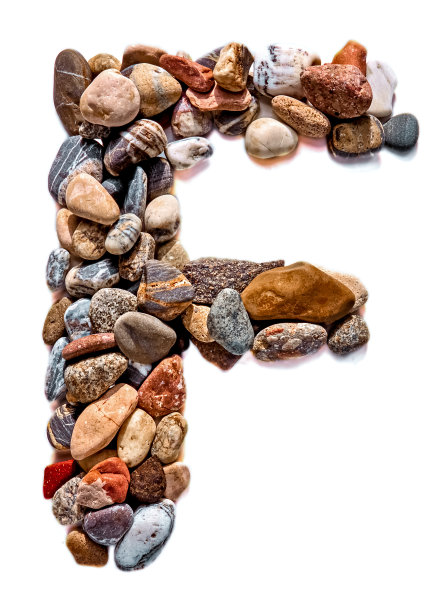 在白色孤立的背景上用光滑的石头刻出的字母。河边的石头上排列着一个字母，细节，特写。有选择性的重点图片下载