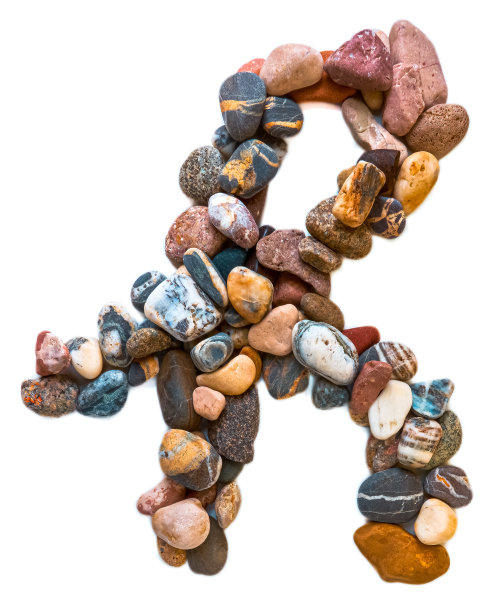 在白色孤立的背景上用光滑的石头刻出的字母。河边的石头上排列着一个字母，细节，特写。有选择性的重点图片下载