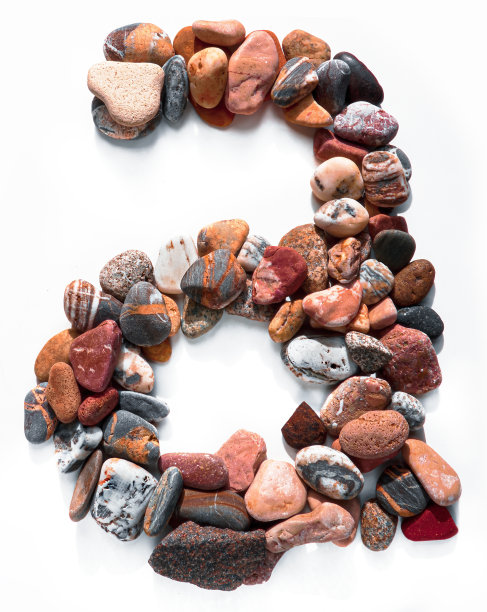 在白色孤立的背景上用光滑的石头刻出的字母。河边的石头上排列着一个字母，细节，特写。有选择性的重点图片下载