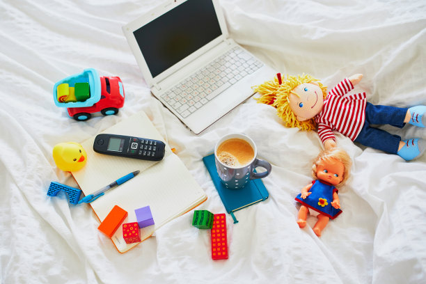 笔记本电脑，咖啡，笔记本电脑，手机和不同的玩具在床上干净的白色亚麻布图片下载