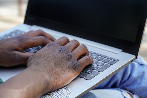 一个黑人在公园用笔记本电脑远程工作的特写镜头图片下载