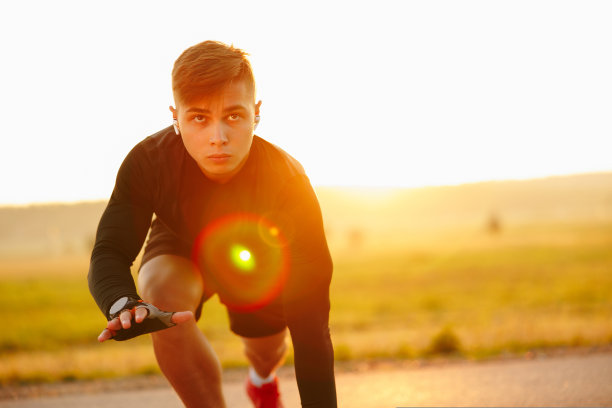 一个年轻的运动员站在体育场跑步机的起点图片下载
