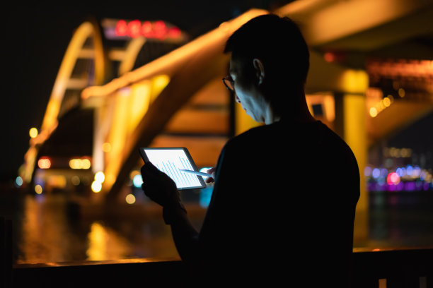 晚上在户外使用平板电脑的男子图片下载
