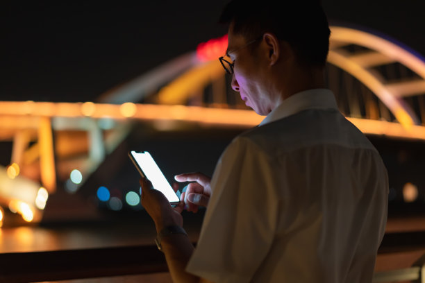 晚上在户外使用智能手机的男子图片下载