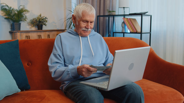 微笑快乐的男人数着钱现金，用笔记本电脑在家里计算家庭收入收入图片下载