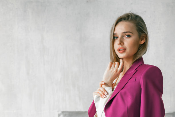 年轻的女商人。美女董事、主管、总经理、ceo，穿着时髦明亮的商务粉色、紫红色套装，坐在扶手椅上拍照。商业目标远大的女野心家图片下载