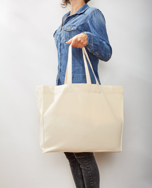 穿着牛仔衬衫的年轻女子拿着一个空白的环保手提袋（无法辨认）图片下载