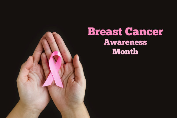 乳腺癌宣传月。成人手持黑色背景的粉色丝带。10月乳腺癌国际标志。医学及卫生保健图片下载