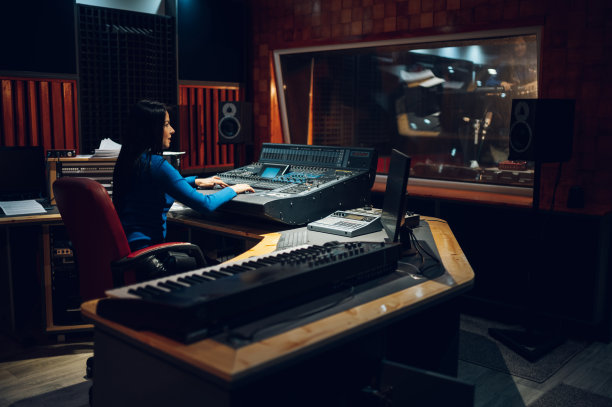 在录音室里制作混音音板的女音乐制作人。图片下载