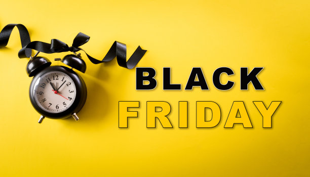 黄色背景上的黑色闹钟的顶视图。购物概念节礼日与黑色星期五构成。图片下载