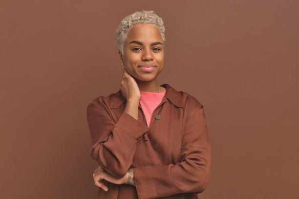 年轻漂亮的非裔美国女性微微微笑，手放在脖子上图片下载