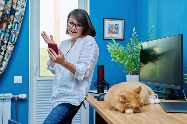 妇女在家庭办公室用智能手机进行视频通话，猫在桌子上睡觉图片下载