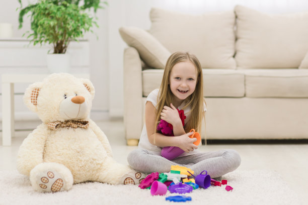 小女孩在地板上拿玩具的照片。图片下载