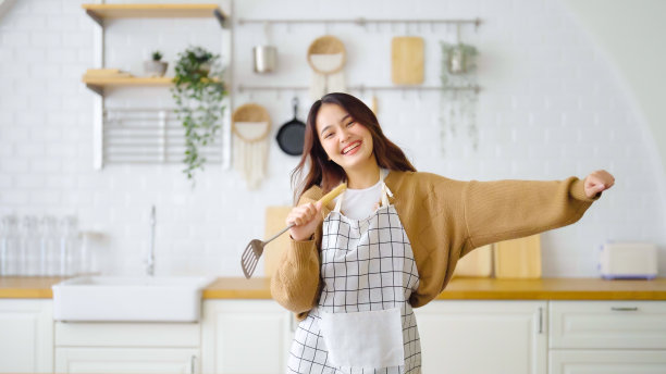 亚洲年轻女子在厨房里跳舞。在周末的空闲时间，她很开心，很放松图片下载