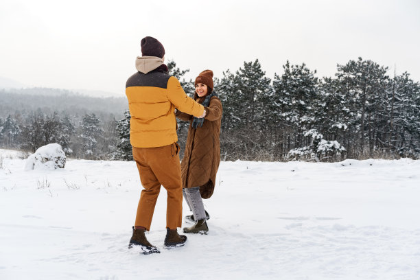 在白雪覆盖的冬季森林里，一对年轻的情侣在户外相爱。图片下载