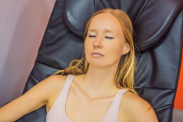 美丽的年轻女子在机场或商场的按摩椅上放松图片下载