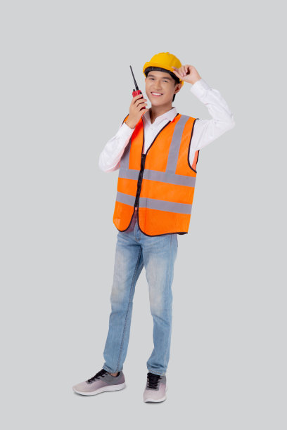 肖像年轻的亚洲男子是工程师，戴着头盔站着，用收音机说话，自信地孤立在白色背景下，英俊的男性是建筑师或承包商，工人或劳工概念。图片下载