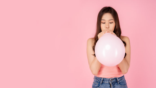 快乐的年轻亚洲妇女吹粉色气球准备聚会美丽的女孩在粉色背景快乐的节日快乐的生日聚会她得到乐趣玩和庆祝与粉彩粉色气球图片下载