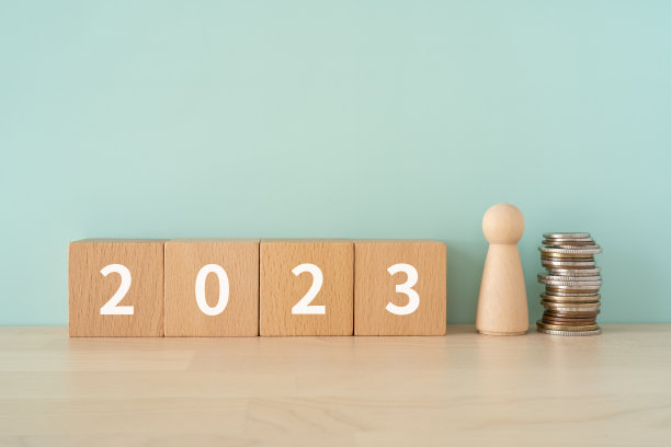 木块与“2023”文本的概念，一个人类玩具，和硬币。图片下载