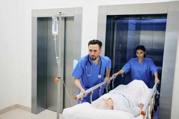 医疗助理和护士将躺在医疗轮床上的患病老年妇女从医院电梯抬到手术室更快图片下载