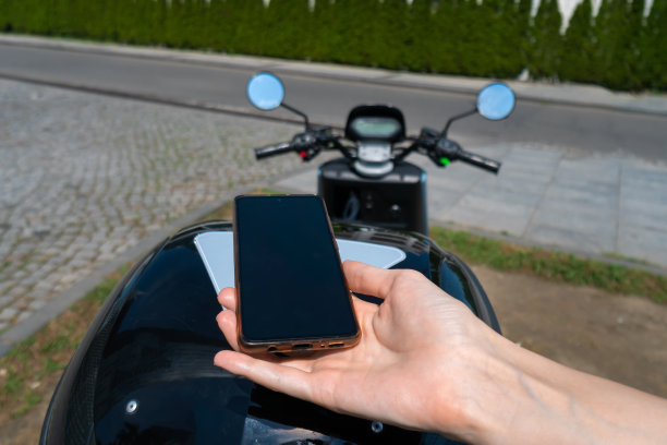 在一个阳光明媚的日子里，一名女子正在用手机扫描摩托车上的二维码。交通租赁概念图片下载