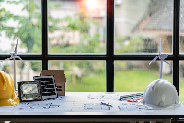 建筑工具和房屋平面图，桌面风车。住宅计划与太阳能电池板和桌面模型的房子设计使用可再生能源的风能和太阳能。图片下载