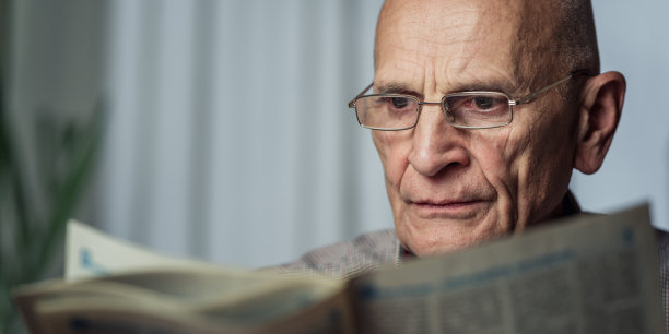 爷爷戴着眼镜一边看报纸一边享受图片下载