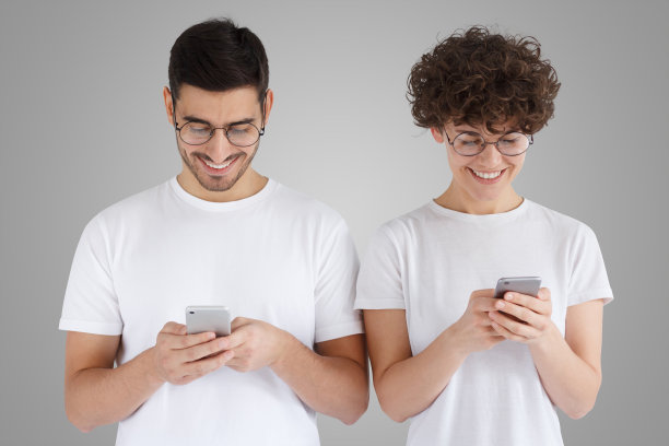 在灰色的背景下，年轻的夫妇拿着手机站在一起图片下载