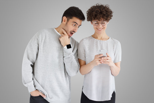 惊讶的年轻男子张大嘴巴看着女友的智能手机图片下载