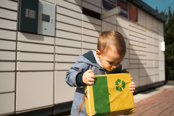 小包裹。孩子们在自动投寄终端机旁的快递箱旁张望。自助式邮政终端机及包裹递送概念。图片下载