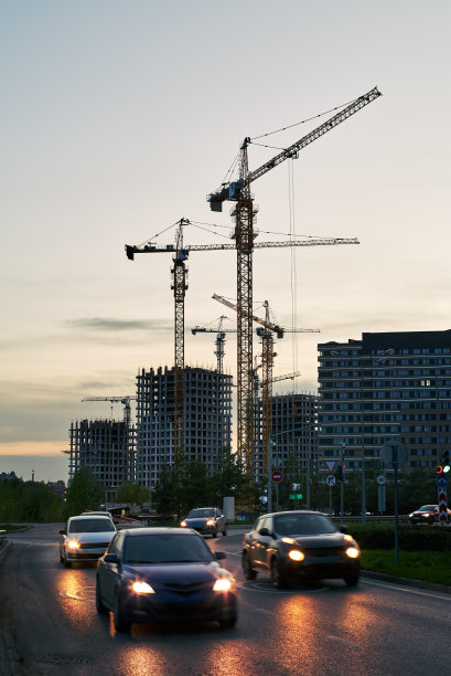 傍晚蓝天夕阳下，建筑工地上的塔吊和建筑物轮廓图片下载