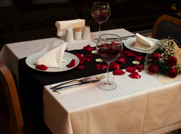 为情人节准备的桌子，红玫瑰花瓣和一杯酒图片下载