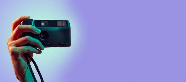 一位女性手拿着一台双色背景的老式胶卷相机图片下载