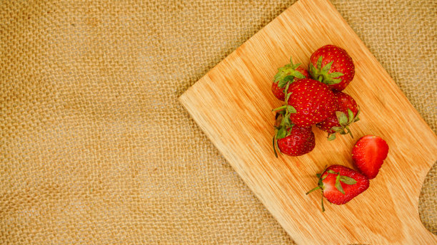 新鲜的草莓放在玻璃碗里平放在砧板上图片下载
