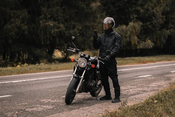 秋天，骑摩托车的男子戴着手套，手里拿着智能手机。图片下载