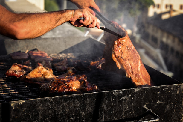 主厨做意大利烤肉。拿着镊子的人在烤肉架上烤肉图片下载